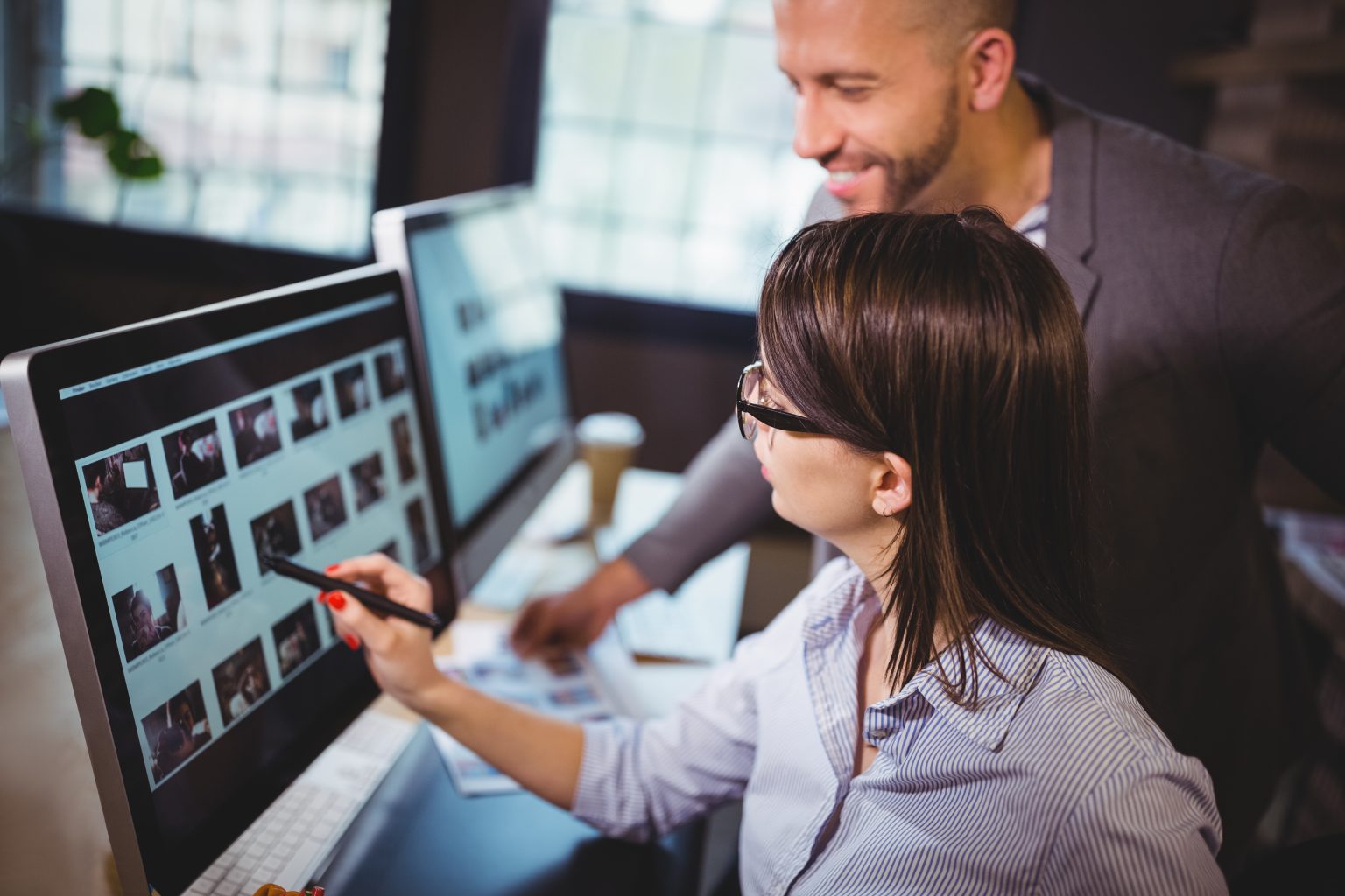 Female photo editor discussing over computer with male colleague in creative office